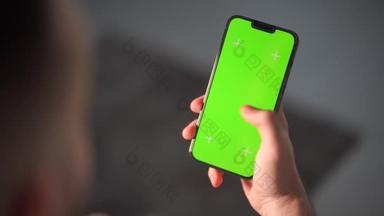 一个男人的手拿着一个有垂直屏幕的智能手机。手持带有绿色屏幕的手机进行键控和跟踪的人